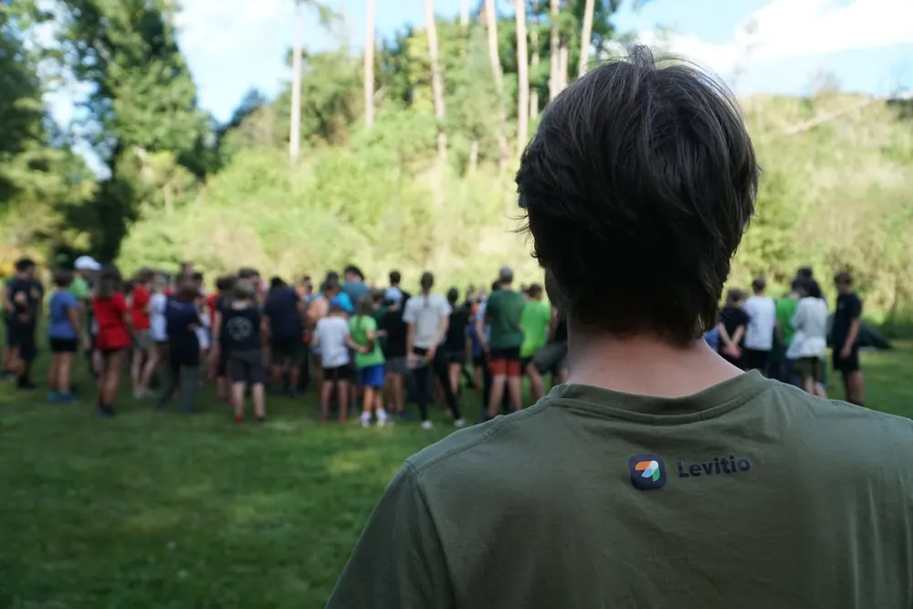 Vedoucí v triku Levitio před skupinou dětí v terénu